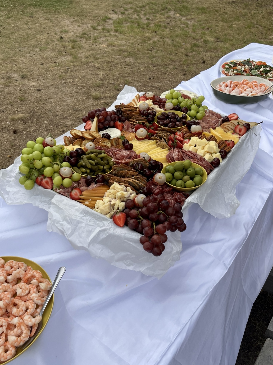 Family-style grazing table with cheeses, fruit, charcuterie and shrimp