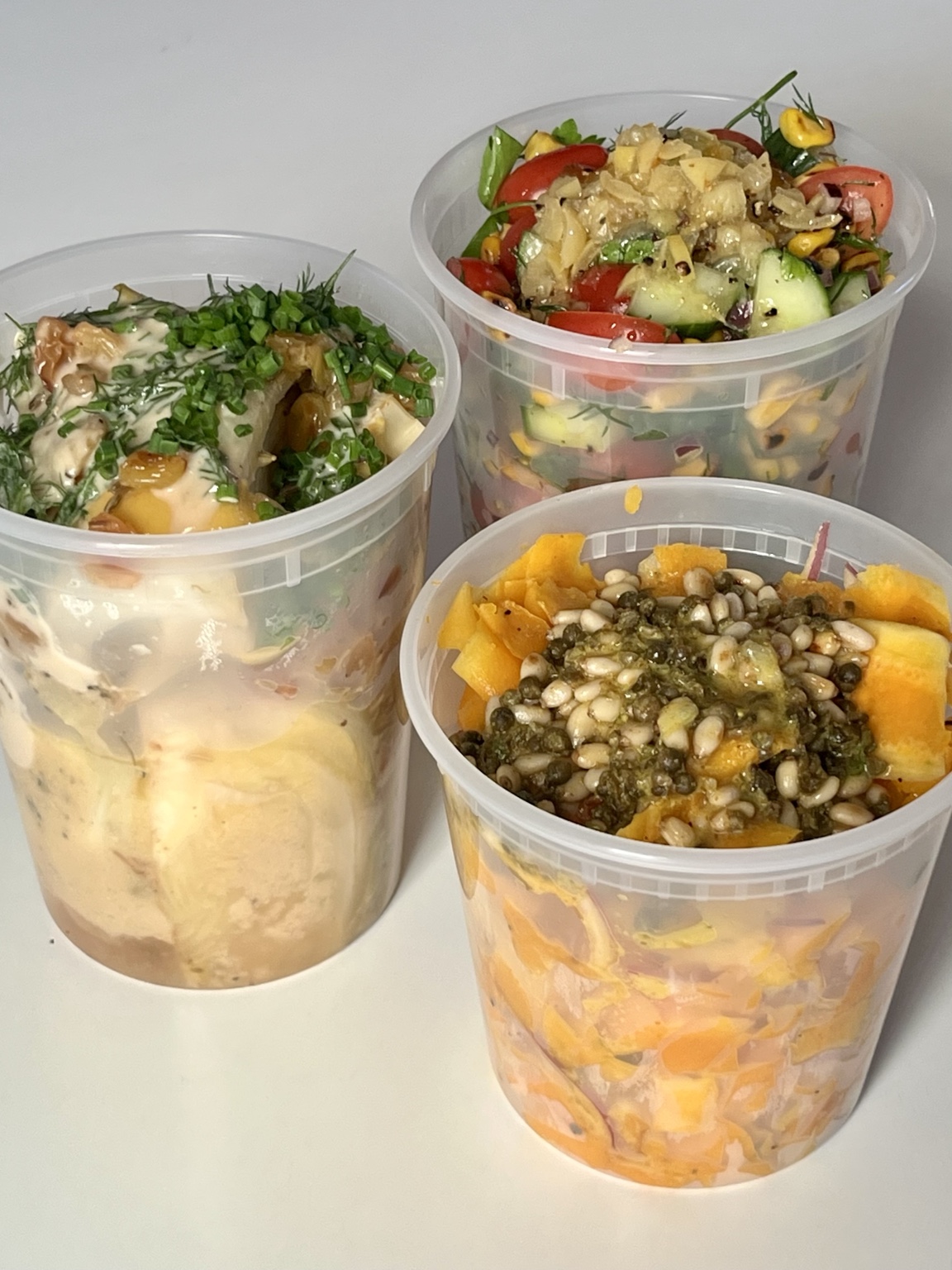 Three prepared vegetable dishes in clear meal-kit containers
